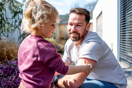 Diabetic dad showign his young son CGM sensor on his arm.