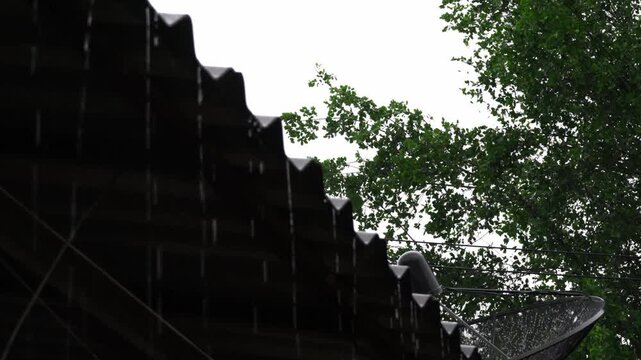 Rainy Season Ambiance: Raindrops dripping from Roof, Water on Pavement and Green Grass Details, Terracotta Wind Chime and Satellite Dish in Monsoon Weather.