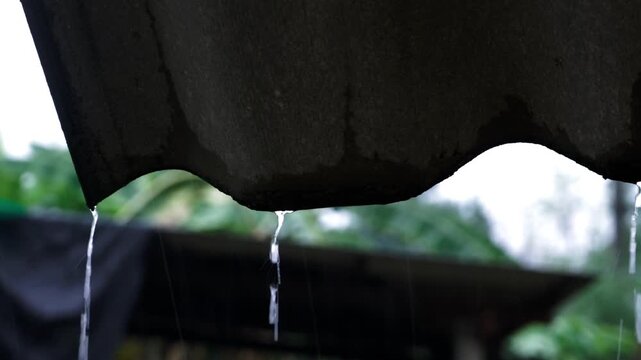 Rainy Season Ambiance: Raindrops dripping from Roof, Water on Pavement and Green Grass Details, Terracotta Wind Chime and Satellite Dish in Monsoon Weather.