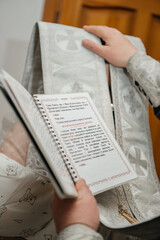 Fototapeta premium A solemn moment during an Orthodox Christian churching ritual. An Orthodox priest reads a prayer from a service book while covering the mother's head with an epitrachelion (stole), symbolizing divine 