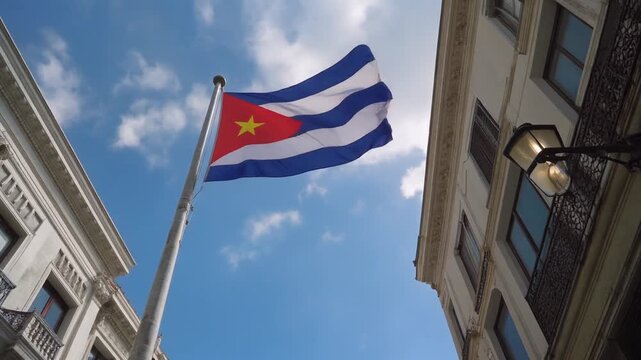 AI-generated vibrant video of the national flag of Cuba displaying its blue and white stripes and red triangle with a white star, waving against a blue sky.