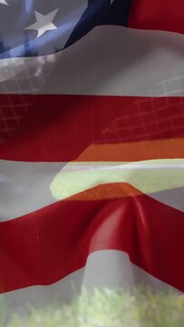 Vertical video: Camera rising US flag overlay rippling over soccer ball, net on pitch for sports ad