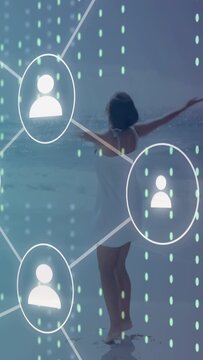 Vertical video: Woman arms opening on beach sparking tech layer icons and dots walking to link nets