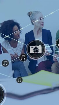Vertical video: Team using devices, camera icon appearing, linking music nodes over table for media