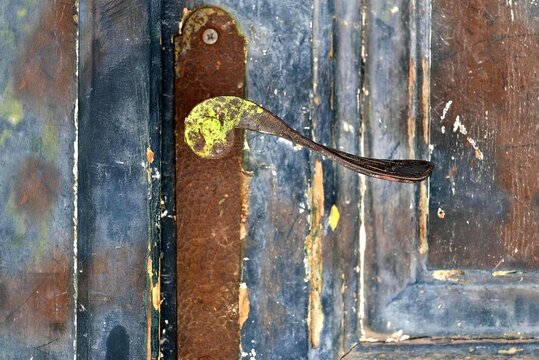 Antique weathered wooden entrance door with a rusty metal handle.