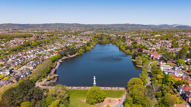 A stunning high-angle aerial drone photo of Roath Park Lake in Cardiff, Wales on a clear sunny day.
