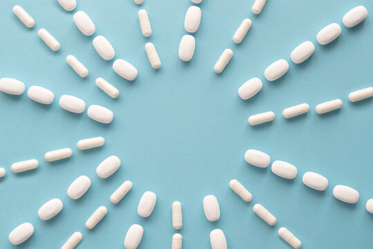 Scattered white pills on blue table. Medical, pharmacy and healthcare concept. Copy space. Empty place for text or logo. Mock up for special offers as advertising, web background or other ideas