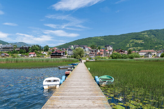 Boats moored along a wooden boardwalk by Lake Plav with Plav in the distance, Montenegro