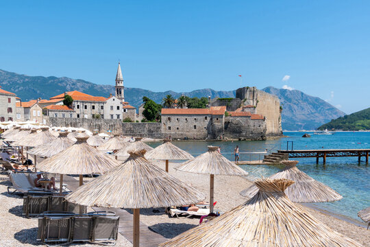 Straw parasols on a sandy beach by the old town (Stari Grad), Budva, Montenegro