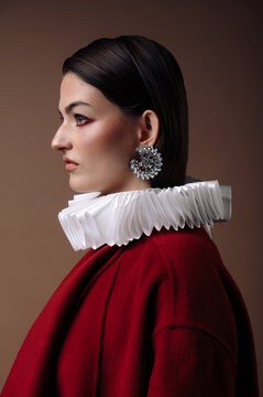 Close-up side view Portrait of a serious young woman in a red dress with a white collar and costume jewellery