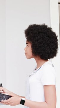 Vertical video: Dipping roller in tray, woman in white top straps painting wall in room, copy space