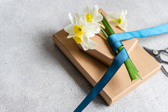 Close-up of a bunch of daffodils tied with ribbon on two cardboard Gift boxes with a pair of scissors on a table