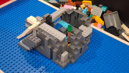 Naklejka premium Official Lego building blocks model of a miniature gray fortress constructed on a blue baseplate on April 20, 2026 in Bangkok, Thailand