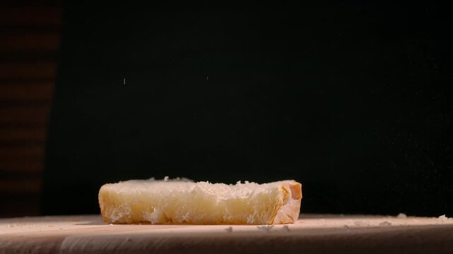 Slices of freshly baked bread falling onto a wooden board against a black background. Concept of baking, culinary arts, and food photography, ideal for use in gastronomy and lifestyle magazines.