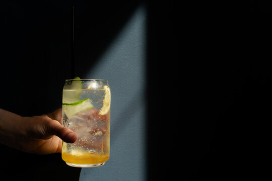 Close-up of a woman's Hand in the sunlight holding a refreshing yuzu melon lemonade drink