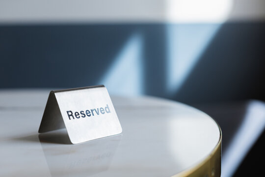 Close-up of a metal reserved sign on a table in a cafe on a sunny day
