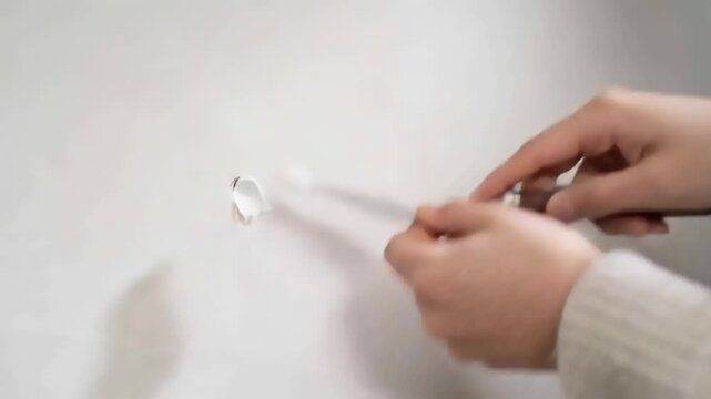 Seeing hole, hands with puttyknife filling hole fixing at home creamknitcuff silverring, copy space
