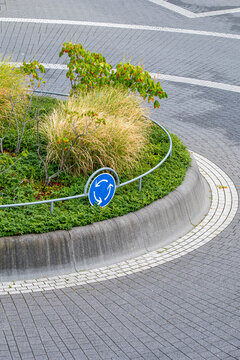 Minimal infrastructure at an empty urban roundabout shows curb island road pavement and signage creating a calm navigational scene with no traffic