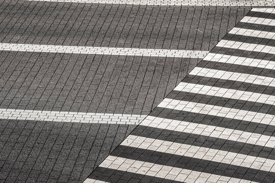 Empty urban crosswalk markings stretch across asphalt pavement where lines and texture create a minimal pattern suitable for editorial background use