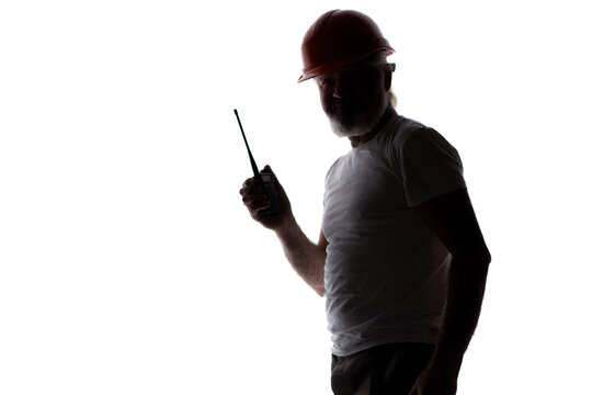Profile of a mature builder or foreman communicating via two-way radio. Backlit studio shot