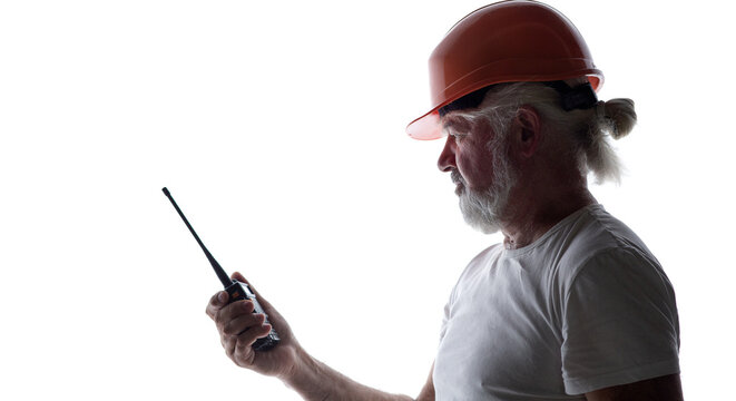 Silhouette of a senior construction worker in a hard hat talking on a walkie-talkie, isolated on a white background