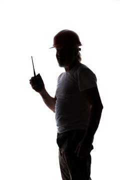 Silhouette of a senior construction worker in a hard hat talking on a walkie-talkie, isolated on a white background