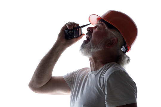Silhouette of a stressed senior construction foreman looking up and shouting into a walkie-talkie, isolated on a white background