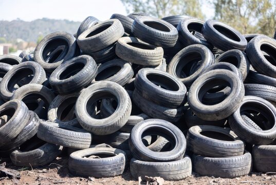 Large pile of used car tires stacked outdoors, representing waste and recycling concepts.
