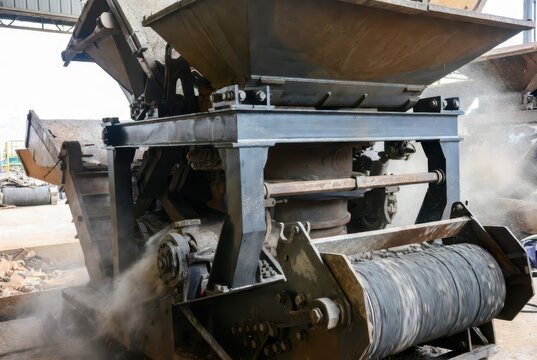Heavy-duty industrial crushing machine processing aggregate with dust and debris flying
