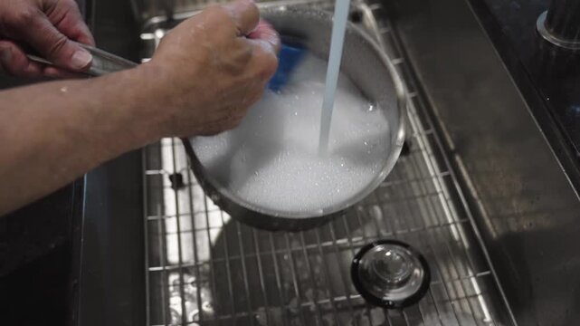 Wahing a stainless steel pot in a stainless steel sink