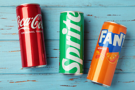 Mykolaiv, Ukraine - March 25, 2026: Iron cans of Coca Cola, Fanta and Sprite drink on blue wooden background.