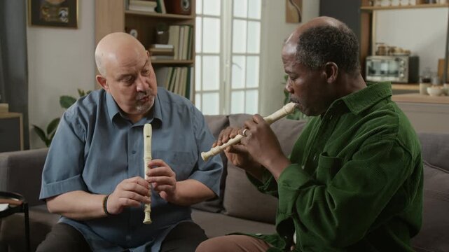 Medium shot of middle aged man teaching senior Black student learning to play recorder during lesson at home Ideal for course promotion or training materials