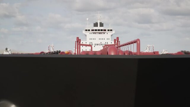 Camera flies towards and over an anchored crude oil super tanker to reveal more anchored ships. Aerial view of oil tankers anchored in the ocean. Strait of Hormuz blockade concept. 3d animation render
