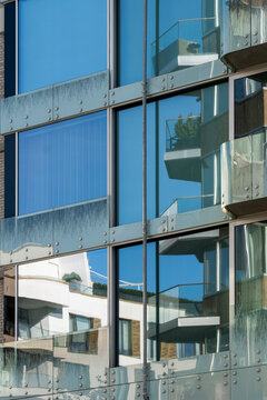 Modern glass building facade with windows and metal bolts forming an industrial pattern while reflection adds depth to clean architecture lines