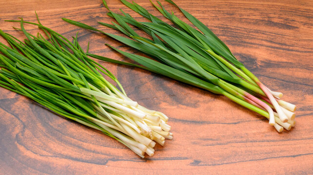 two different types of green onions on a wooden table background