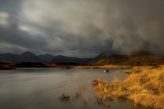 River Ba with mountain peaks of Meall a&acute;Bh&uuml;iridh and Clach Leathad in the background and dramatic clouds, Glen Coe, Rannoch Moor, west Highlands, Scotland, United Kingdom