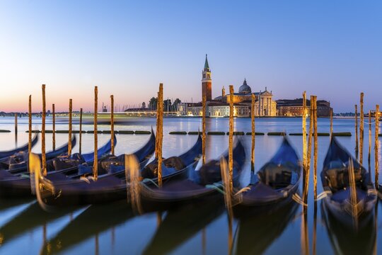 Venetian gondolas at St. Mark's Square in the evening light, blue hour, in the back monastery San Giorgio Maggiore, district San Marco, Venice, region Veneto, Italy