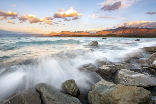 Stones on shore, lake with sunset swell, long time exposure, Lake Tekapo, Canterbury, South Island, New Zealand