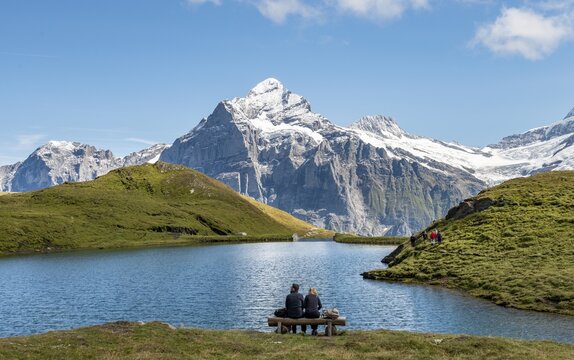 Hikers resting on a bench, Bachalpsee with summit Wetterhorn, Grindelwald, Bernese Oberland, Switzerland