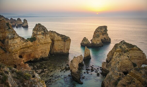 Sunrise over the sea, rugged rocky coast of sandstone, rock formations in the sea, Ponta da Piedade, Algarve, Lagos, Portugal