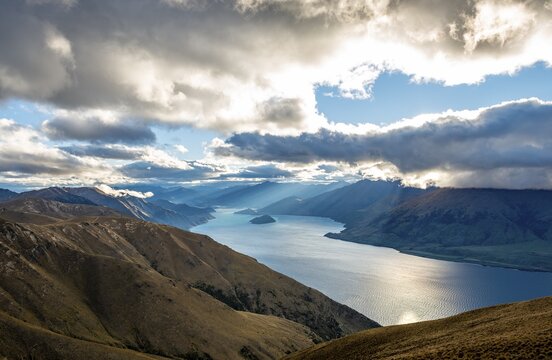 Sunbeams shining through cloudy sky, view of Lake Wanaka in evening light, lake and mountain landscape, view from Isthmus Peak, Wanaka, Otago, South Island, New Zealand