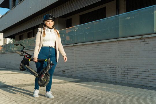 Woman carrying folding electric scooter in city
