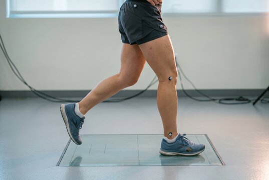 Close-up of woman running on force plate in lab with motion markers