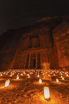 Man with flute, candles in front of the Pharaoh's treasure house, carved in rock, at night, facade of the treasure house Al-Khazneh, Khazne Faraun, mausoleum in the Nabataean city Petra, near Wadi Musa, Jordan