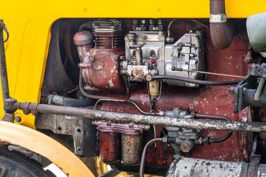 Side view of a vintage tractor engine with yellow bodywork, fuel injection pump, air compressor, rusty mechanical components, oil residue, industrial textures, classic agricultural machinery photograp