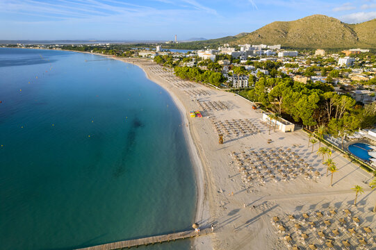 Beach in Mallorca with rows of sun loungers clear blue water at Balearic Islands, Spain