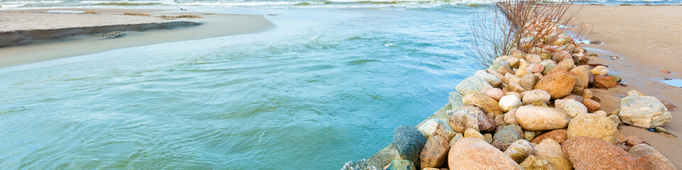 Obraz premium Delta in the daytime. Rocky bank of river. The river flows into the sea