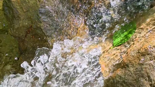 Flowing water over rocks in a stream under bright sunlight on a warm day