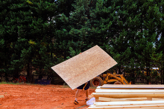 Contractor is moving large plywood at construction site during new home project