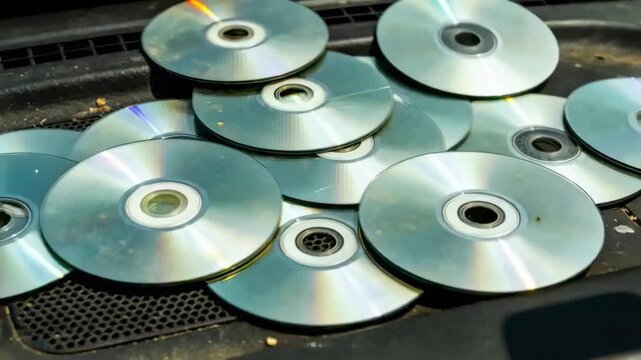 Shifting camera panning on car dashboard, showing stacked CDs, vent, dust, rainbow glints, shadow